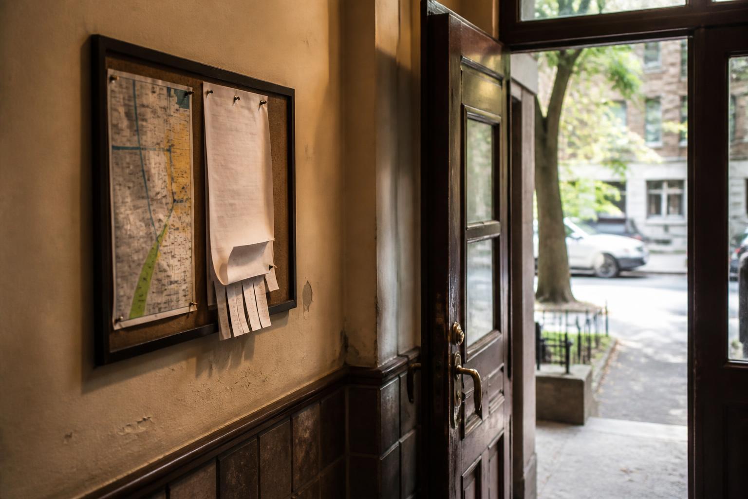Bulletin board with pinned papers beside an open doorway to a street